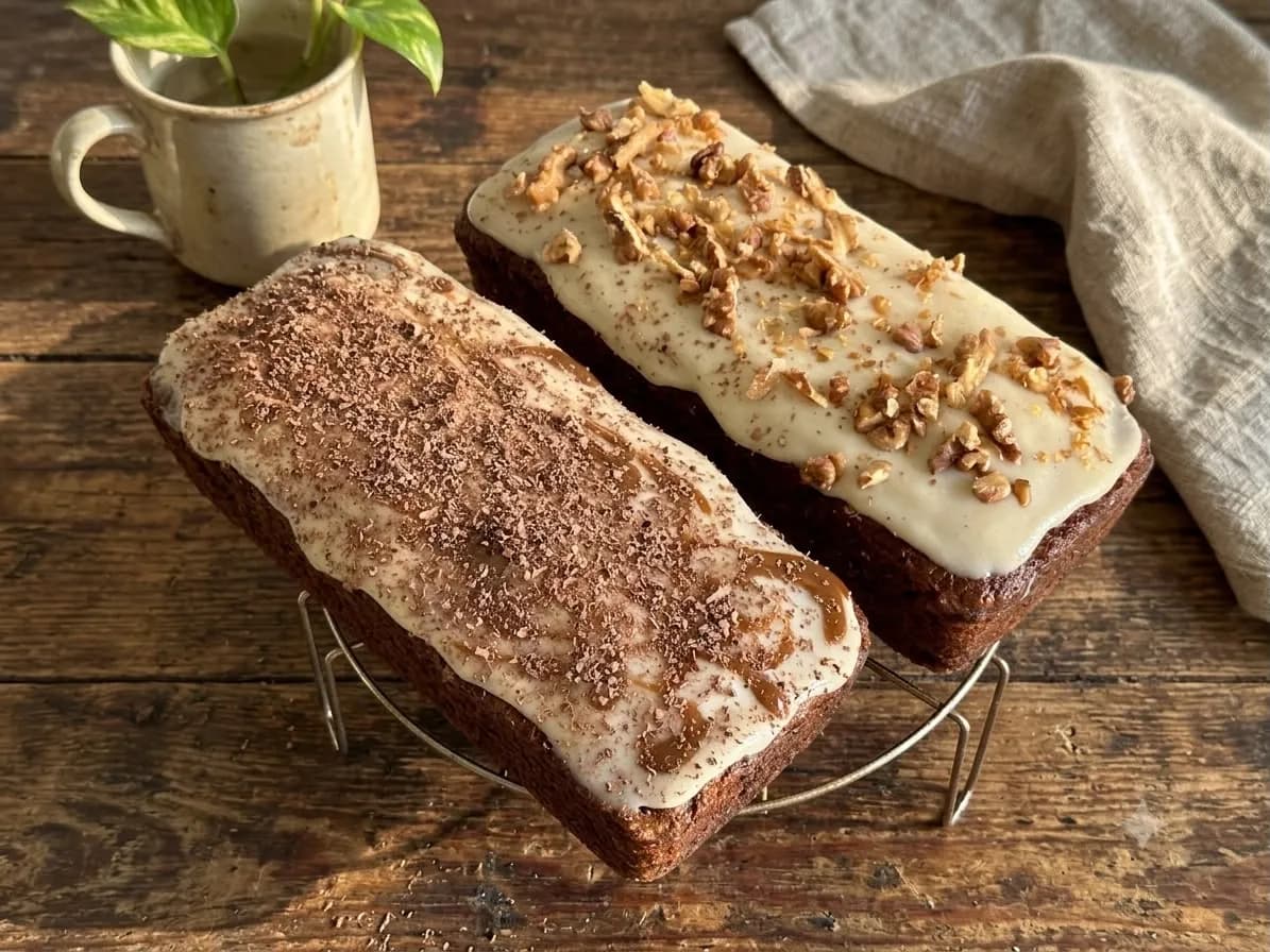 Dos budines de zanahoria con glaseado y nueces picadas sobre una tabla de madera